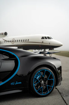 Sleek Gulfstream jet soaring above a winding mountain road where a Bugatti speeds below.