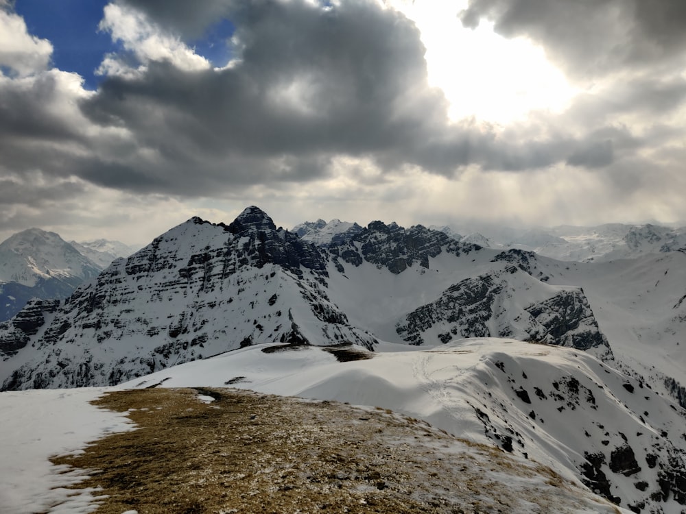 a mountain range covered in snow under a cloudy sky