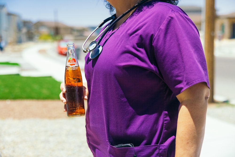 a woman wearing a stethoscope holding a bottle of beer