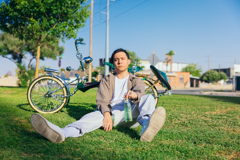 a man sitting in the grass next to a bike