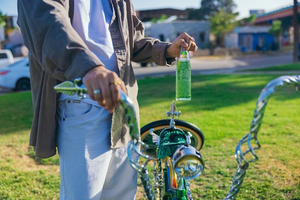a man standing next to a bike with a green bottle attached to it