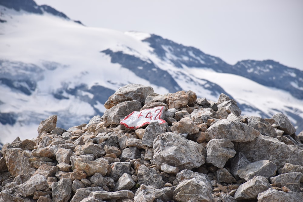 a red and white sign sitting on top of a pile of rocks