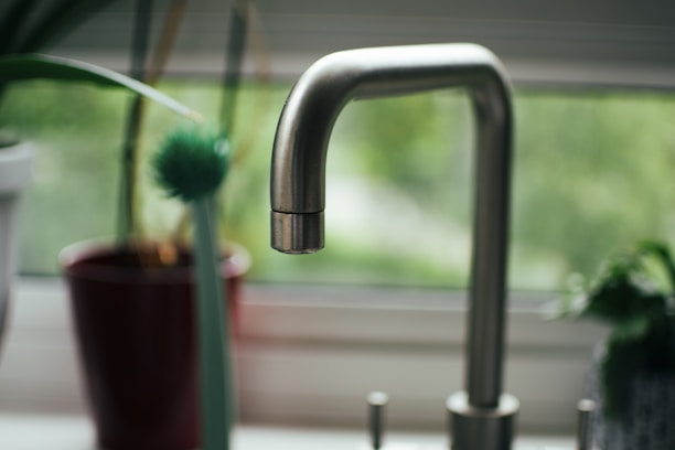 a kitchen sink with a mixer tap next to a window