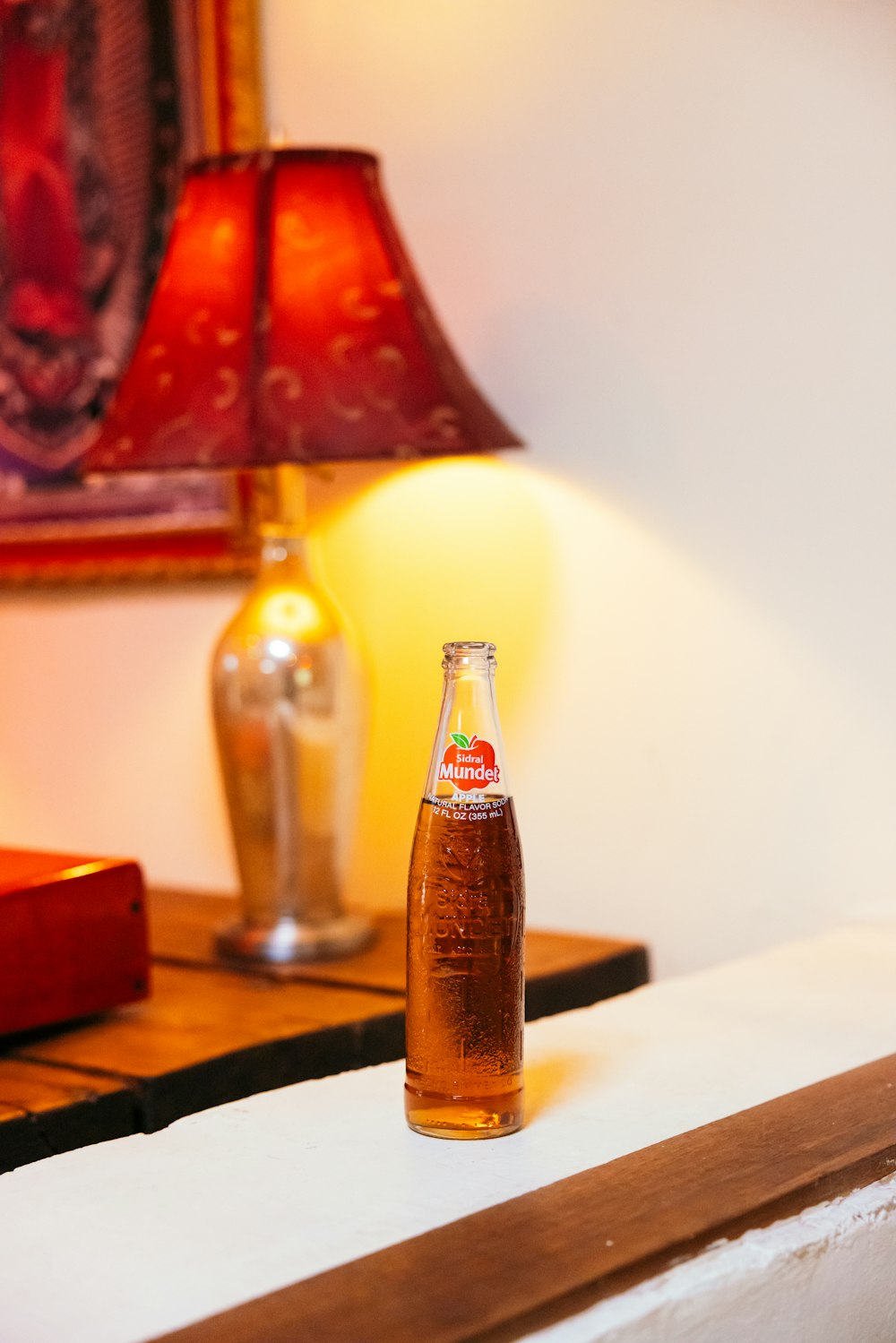 a bottle of soda sitting on a table next to a lamp