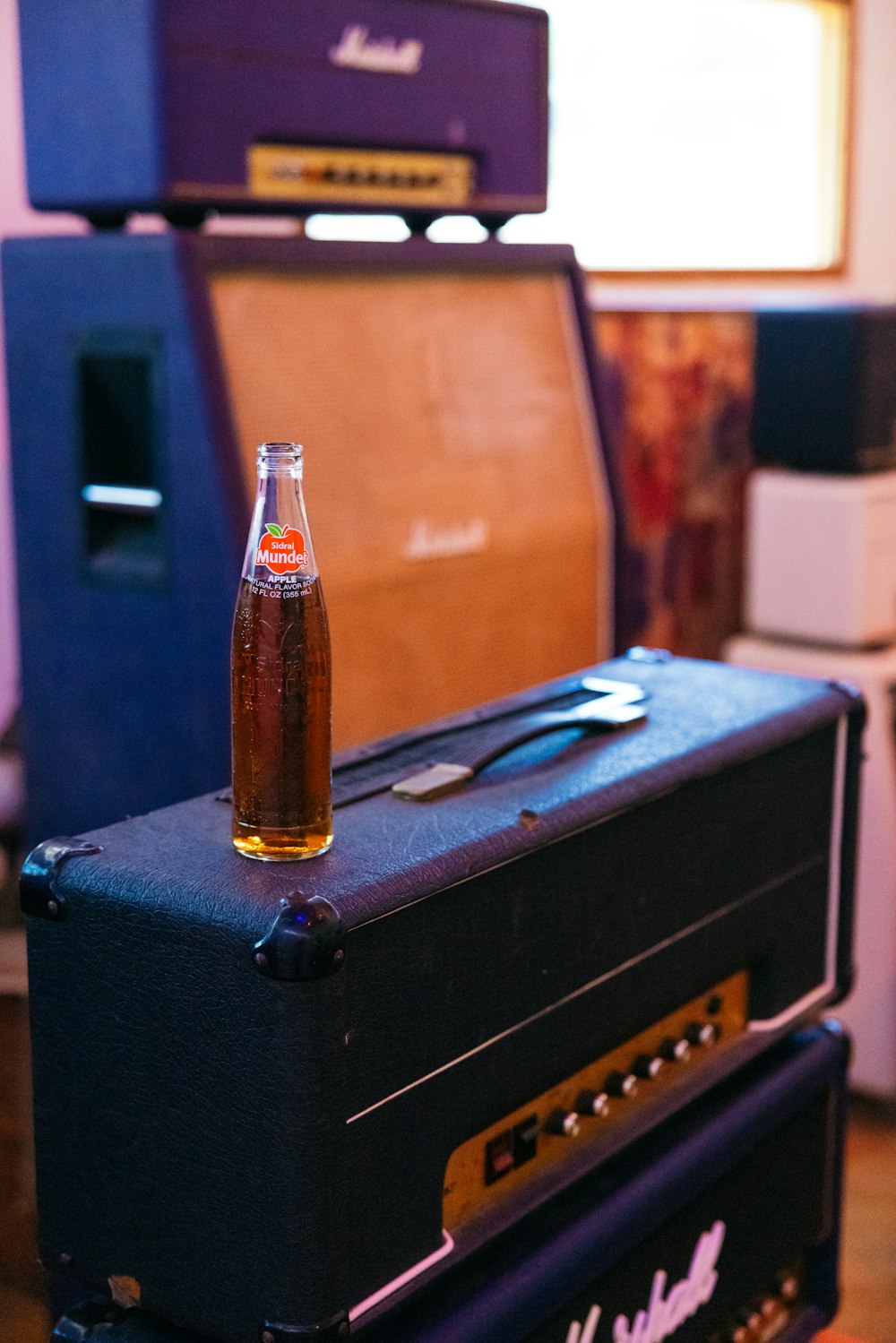 a bottle of soda sitting on top of two amps