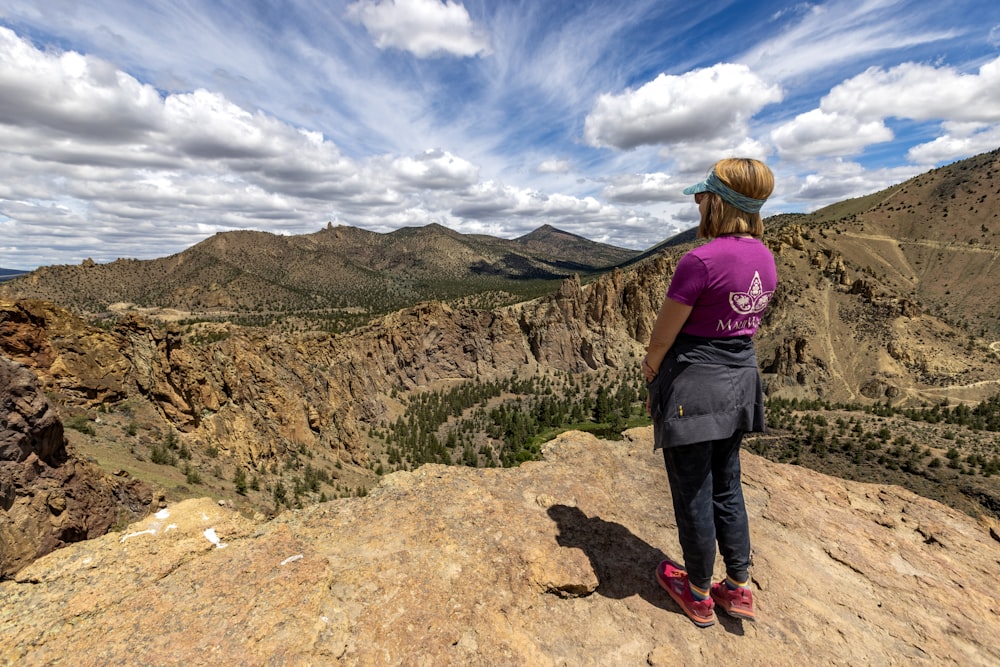 a woman standing on top of a mountain overlooking a valley