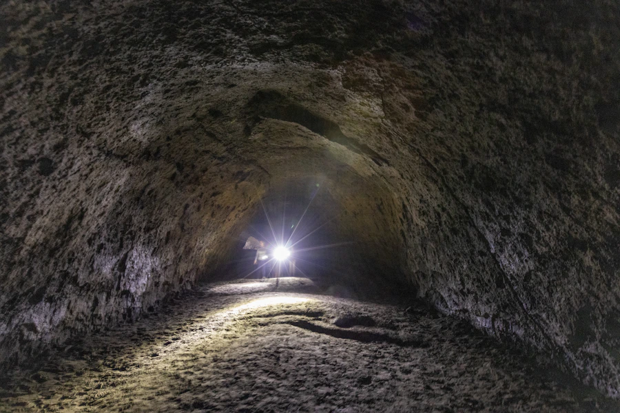 Explorer with flashlight inside Lava River Cave near Bend, Oregon, showing volcanic rock tube walls