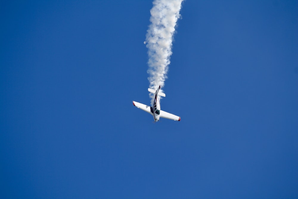 a plane with smoke coming out of it flying in the sky
