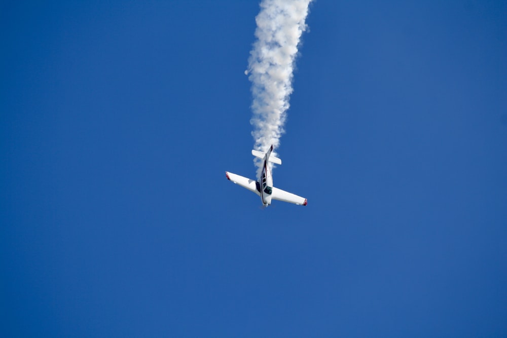 un avion avec de la fumée qui en sort volant dans le ciel