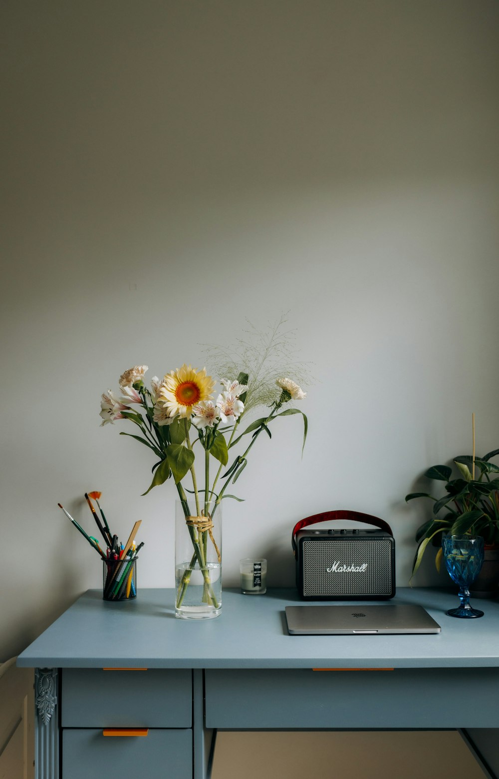 a vase of flowers sitting on top of a blue desk
