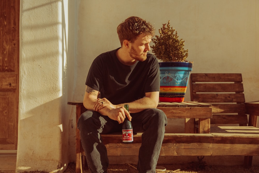 a man sitting on a bench with a bottle of beer