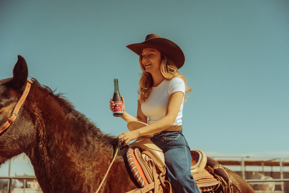 a woman sitting on a horse holding a bottle of beer
