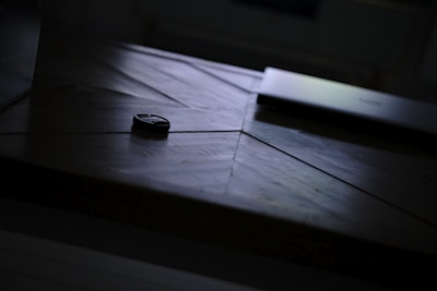 Close-up of the sleek black Bluetooth tracker resting on a modern wooden table.