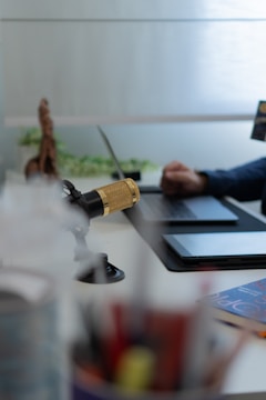 A creative desk setup with notes, a tablet showing content drafts, and a microphone.