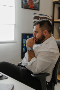 a man sitting at a desk with his hand on his chin