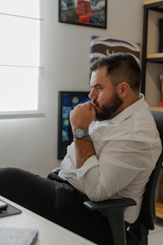 a man sitting at a desk with his hand on his chin
