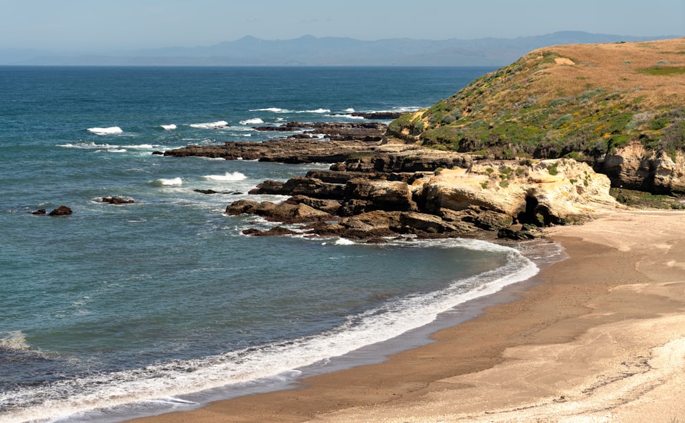 a sandy beach next to the ocean with waves coming in