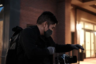 Technician inspecting and repairing a CCTV camera on a rooftop at dusk.