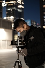 A close-up of a photographer at work, adjusting their camera in an urban environment.