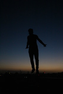 a silhouette of a person jumping in the air