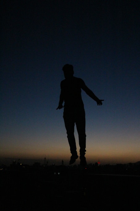 a silhouette of a person jumping in the air