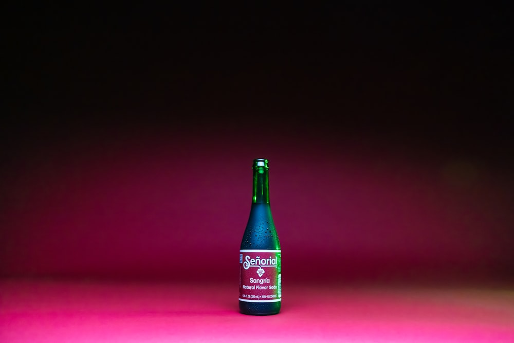 a bottle of alcohol sitting on a pink surface