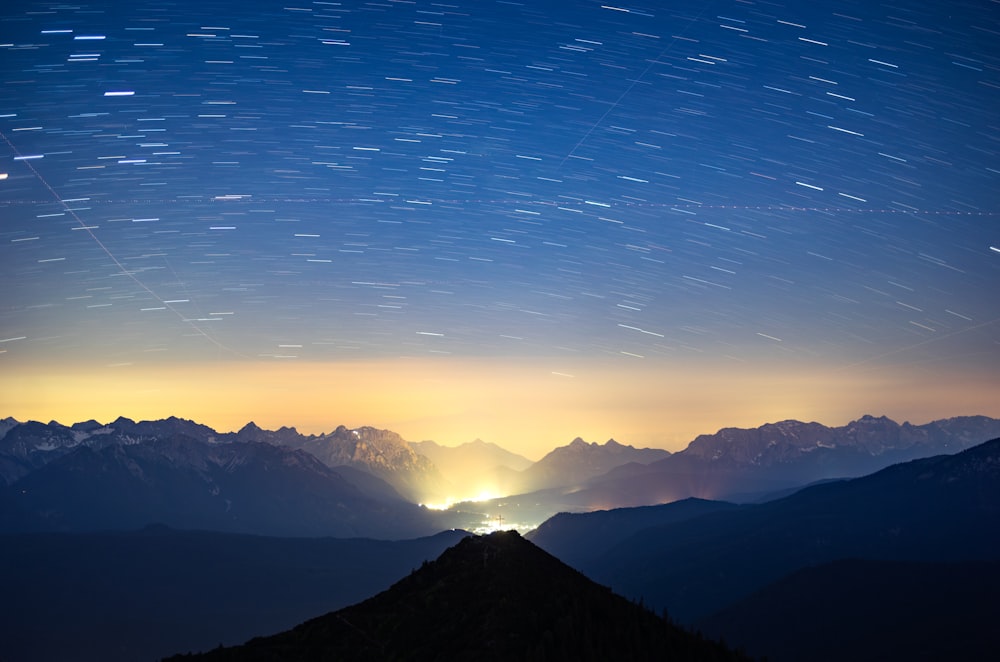 the night sky with stars above a mountain range