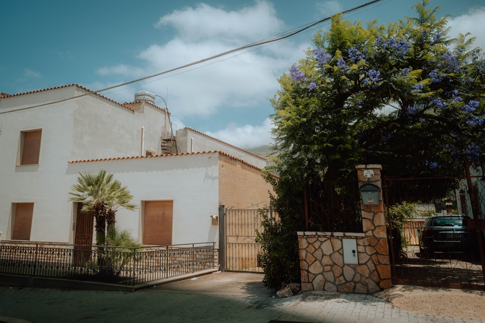 a house with a gate and a tree in front of it