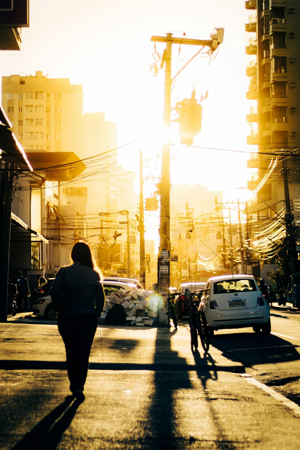 a woman walking down a street next to a traffic light