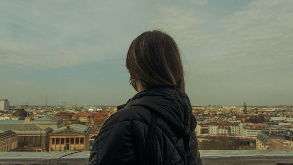 a woman standing on top of a building looking at a city