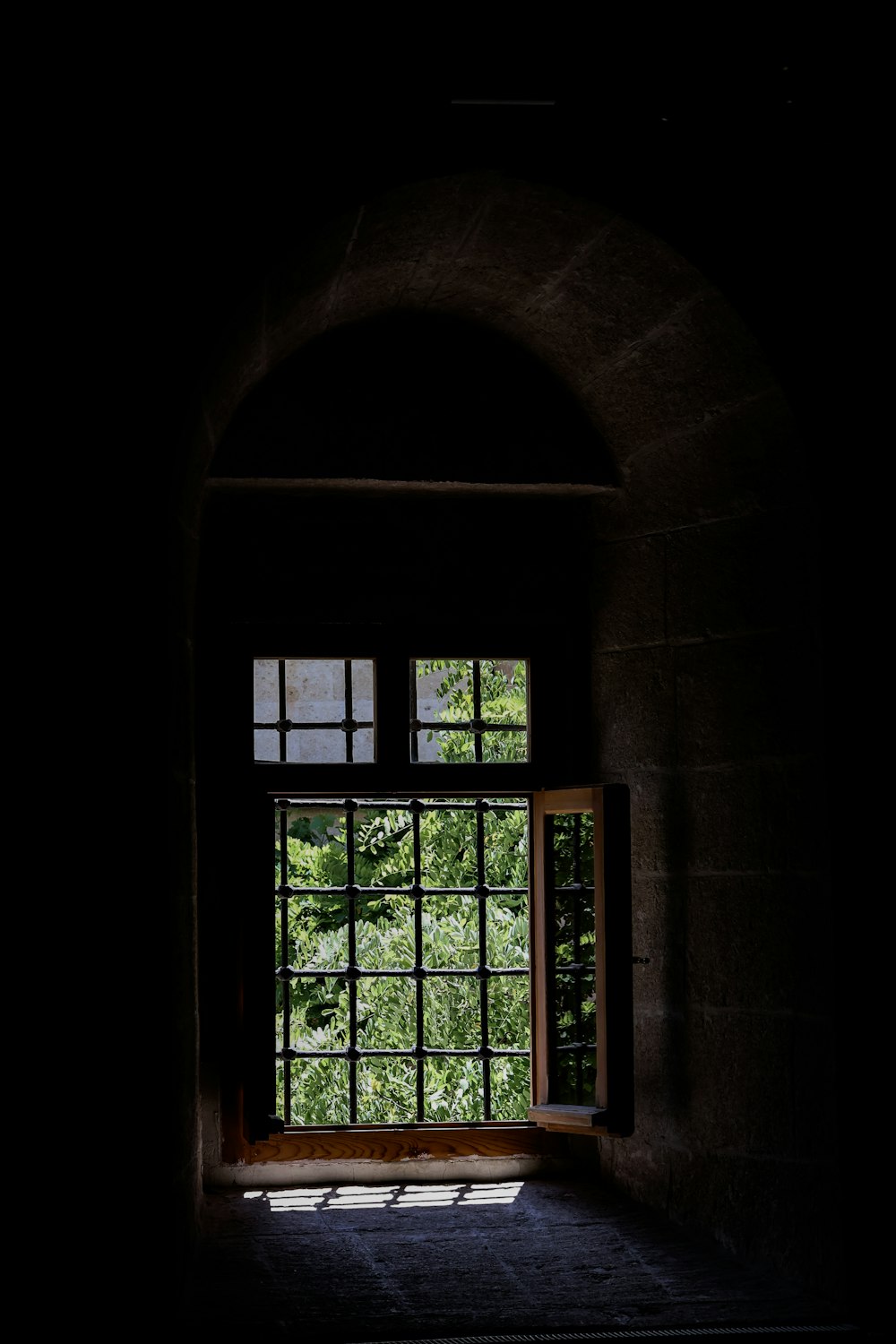 an open window in a dark room with trees outside