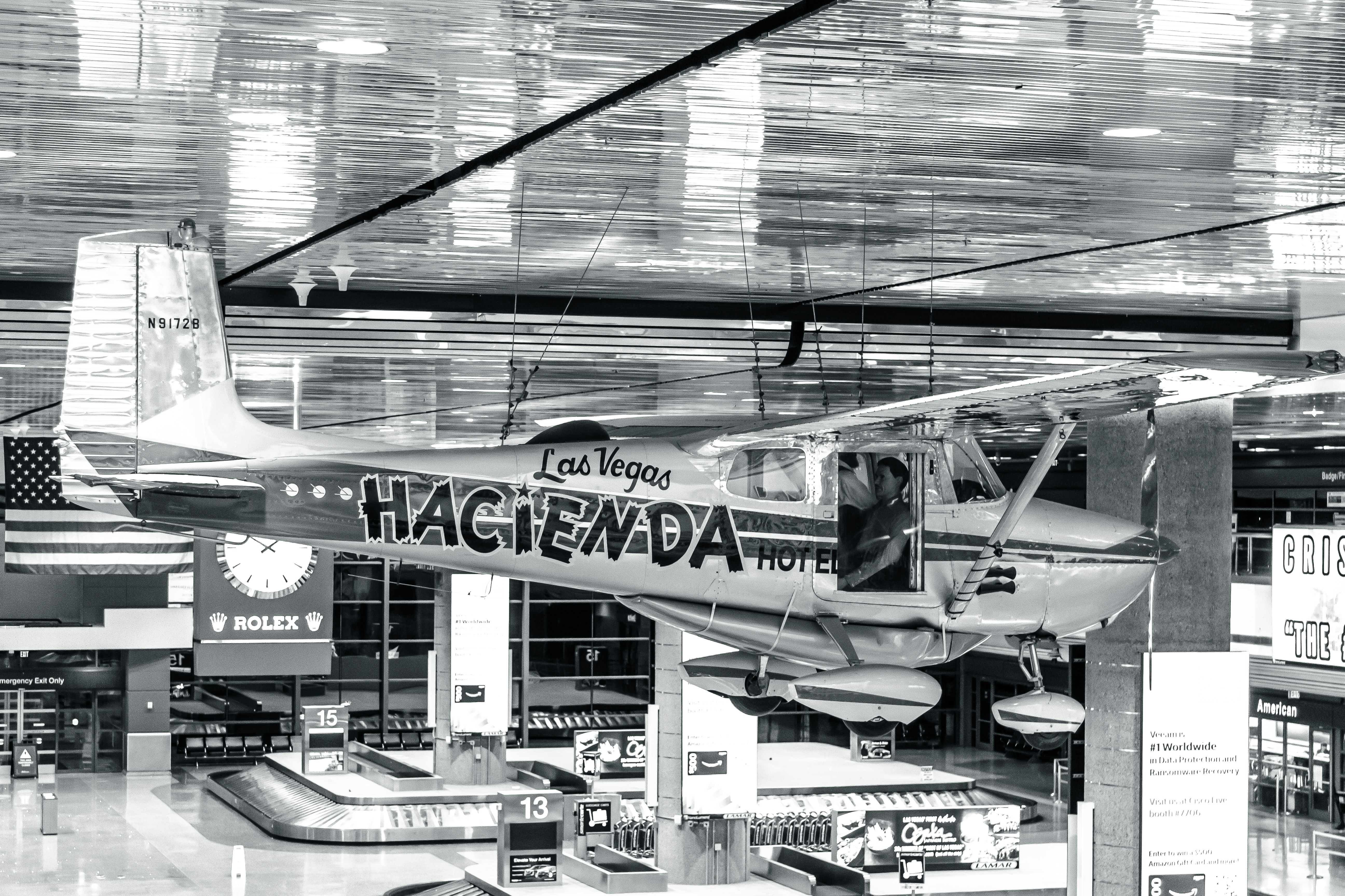 a black and white photo of a plane inside of a building, Las Vegas baggage claim from above, with Cessna.