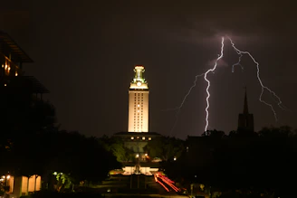 A close-up of The Tower tarot card showing a lightning strike and falling figures against a dark sky.