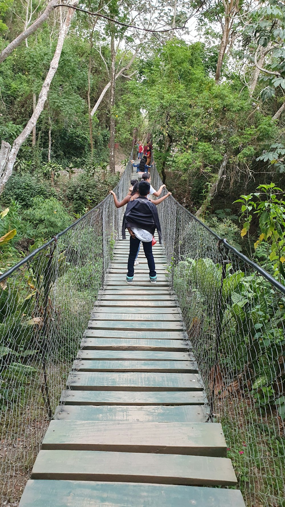 a man and a woman walking across a suspension bridge
