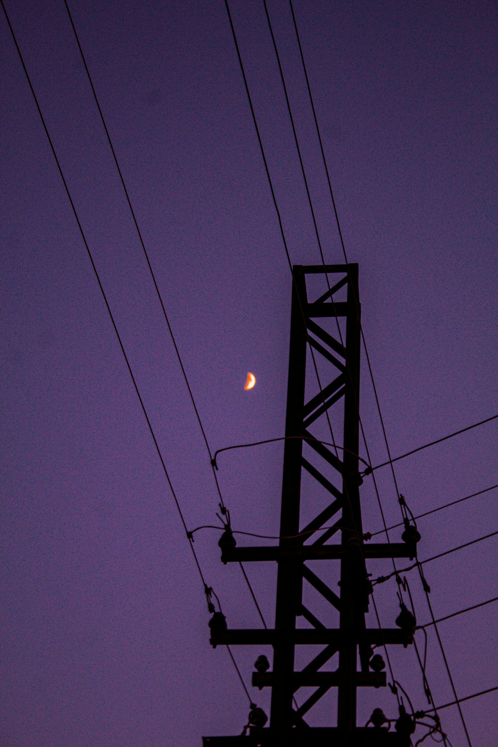 a full moon is seen behind power lines