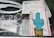 A window displays two USPS Priority Mail labels. One label features a colorful drawing of a cactus in a pot, while the other appears worn and partially covered by white scribbles on the glass.