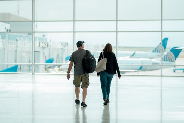 Couple smiling with luggage at an airport, ready for their vacation.