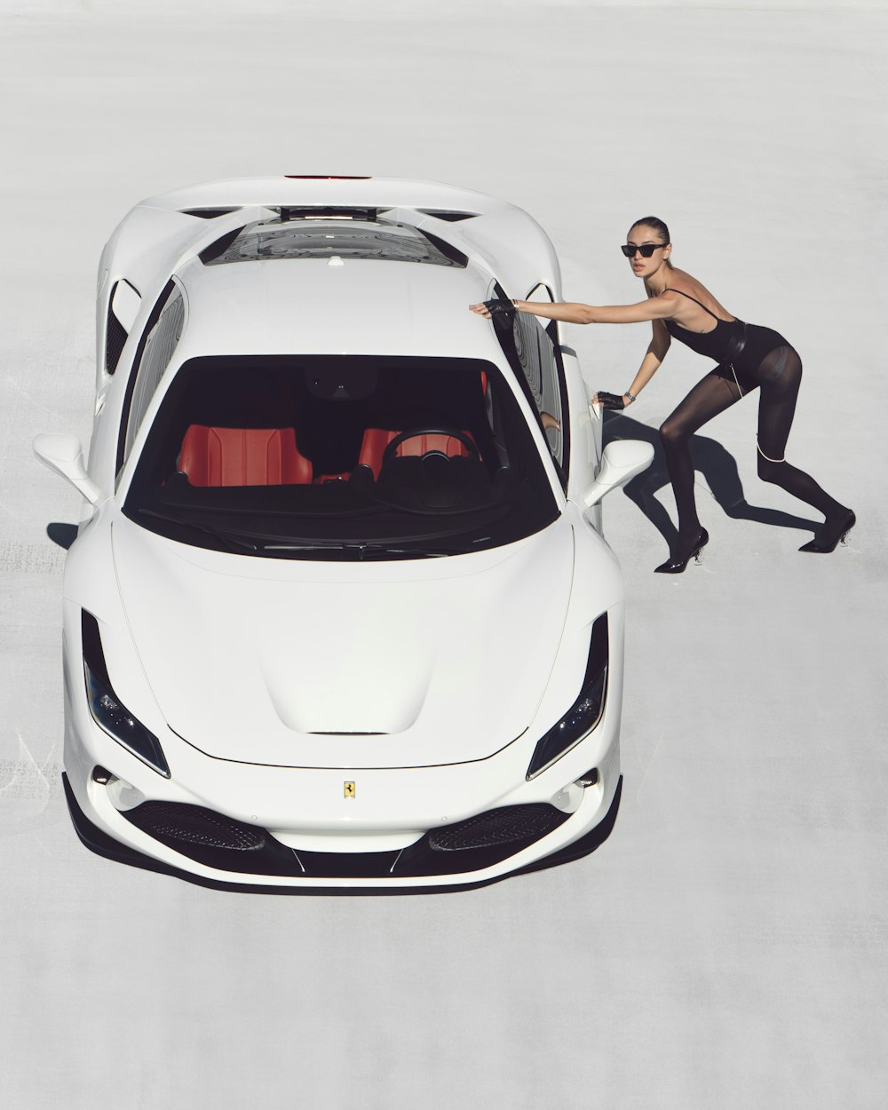 a man in black and white running next to a white sports car