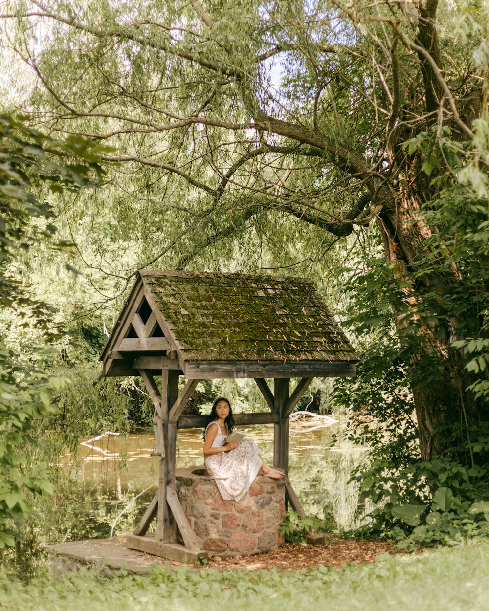 a woman sitting on a stone bench under a tree