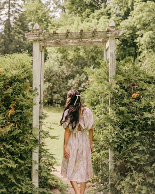 Woman wearing a whimsical cream dress walking through an earthy terracotta-colored garden path.