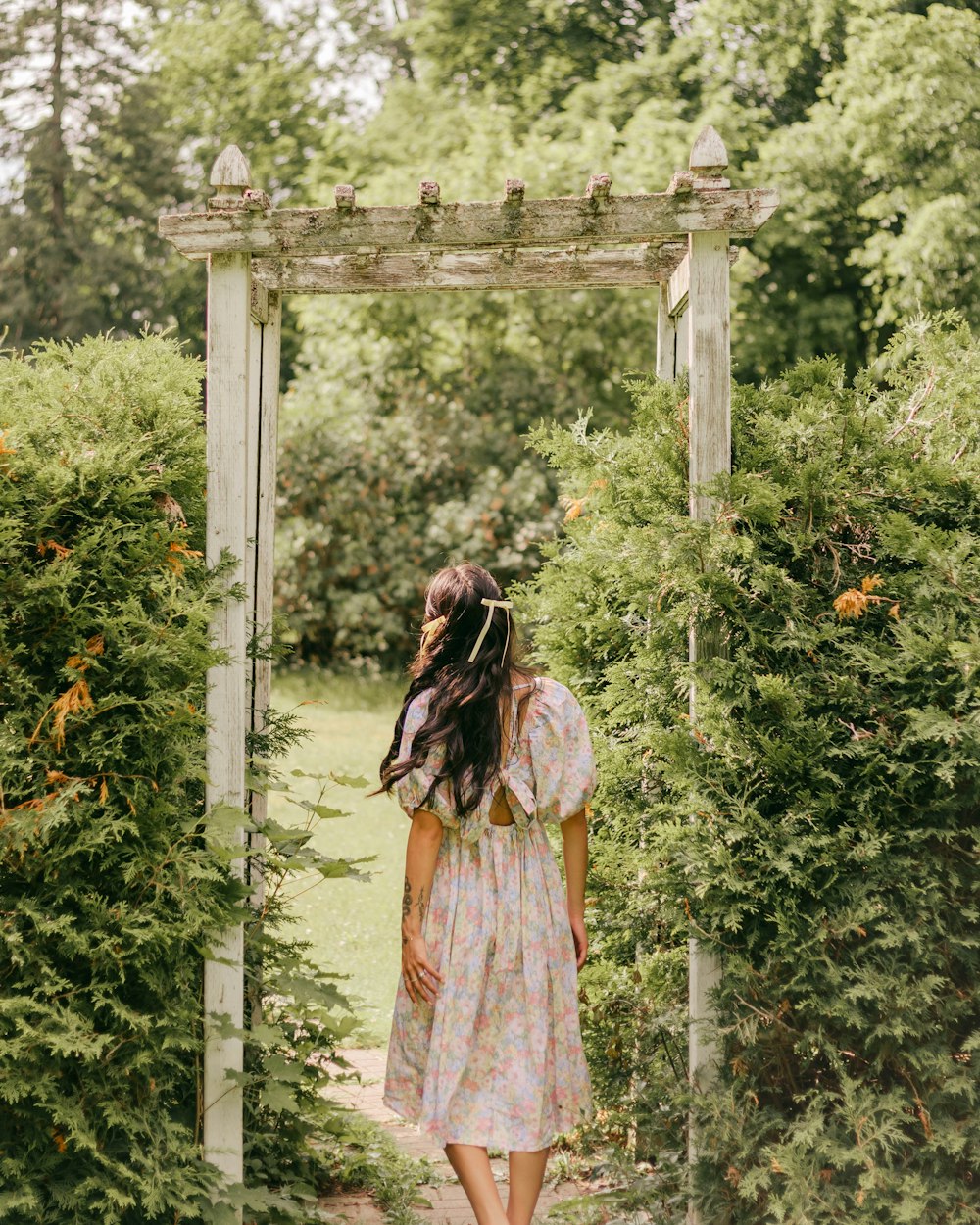 a woman in a dress walking through a garden