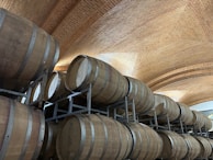 Traditional wine barrels stacked in a cellar with warm, golden lighting.