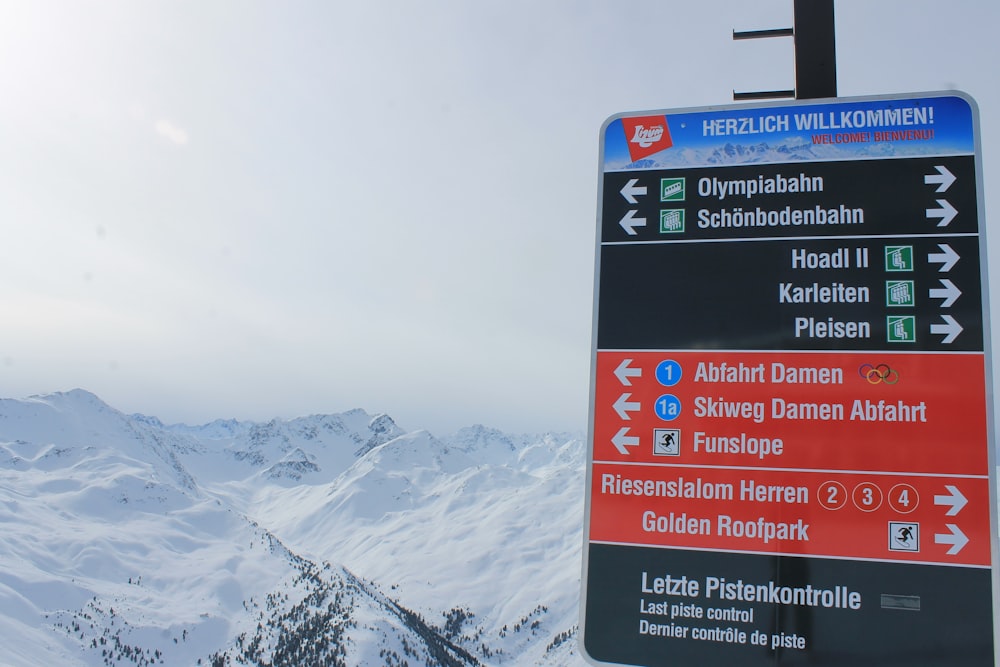 a sign pointing in different directions on a snowy mountain