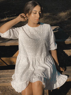 Woman sitting on a city bench wearing a flowing Atelier Lumina dress, soft natural light.