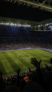 Stadium filled with fans watching a live match under bright lights.