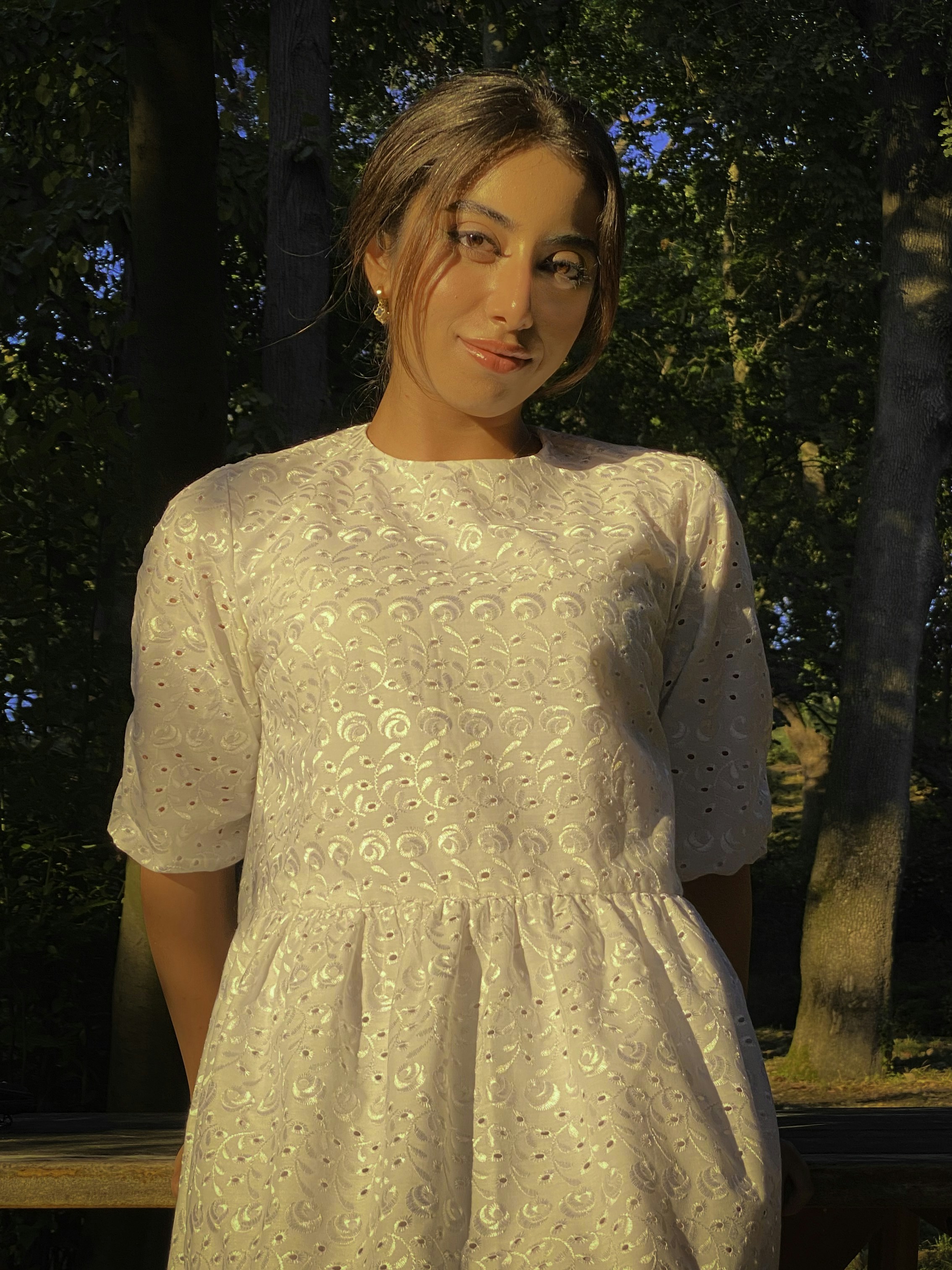 a woman in a white dress standing in front of trees