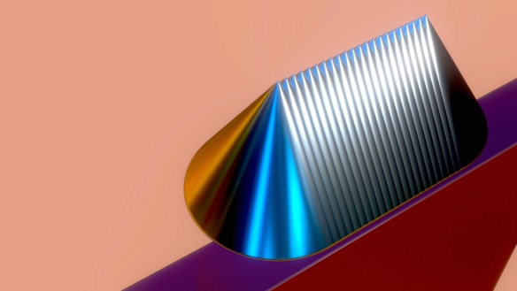 A geometric cone structure with a ribbed surface shown against a smooth gradient background. The cone displays a glossy texture with a mix of metallic colors including blue, silver, and gold. It seems to be placed on a solid-colored base that contrasts with the pale peach background.