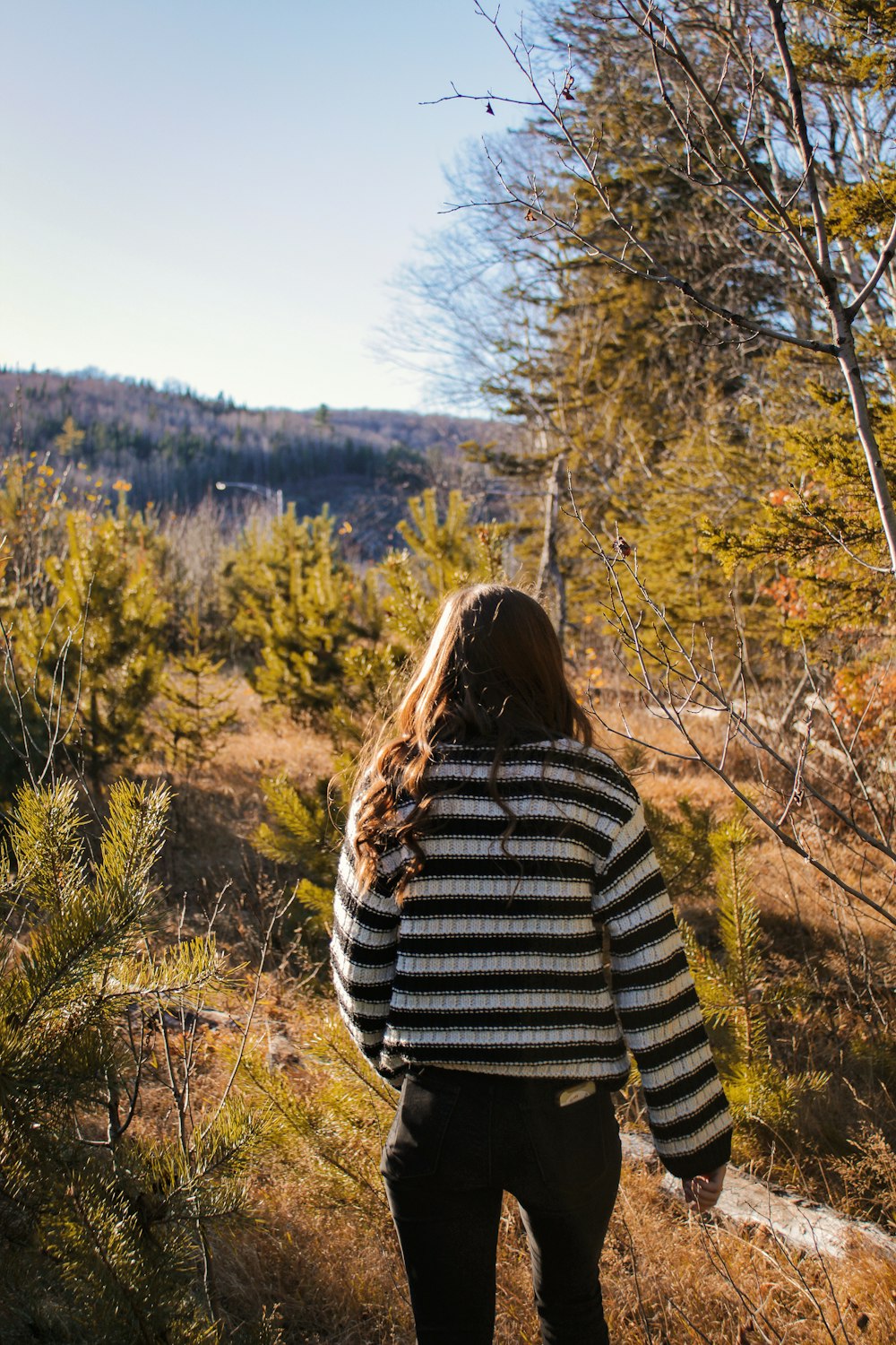 a woman standing in a field with trees in the background