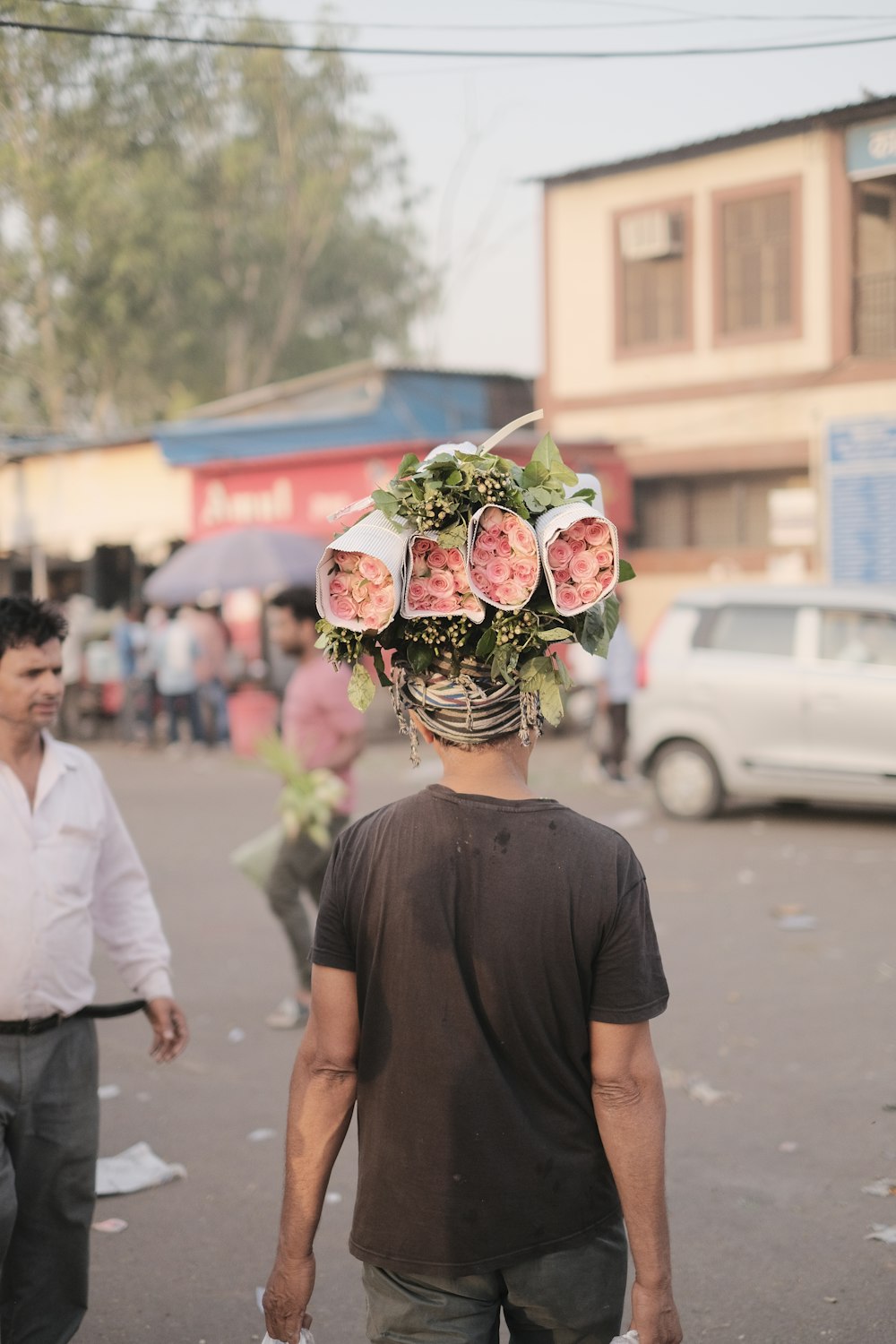 a man walking down a street with a bunch of flowers on his head