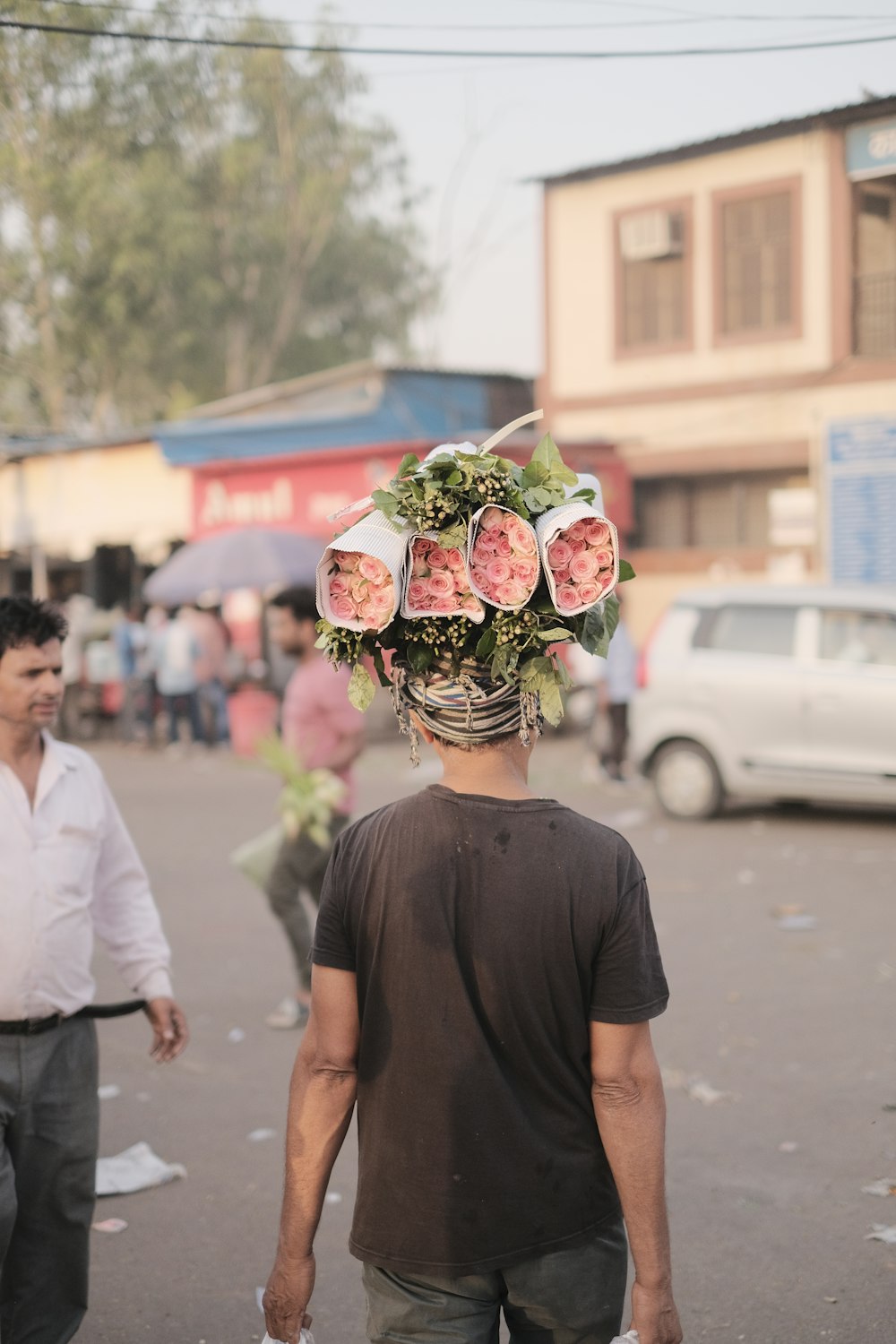 Un hombre caminando por una calle con un ramo de flores en la cabeza